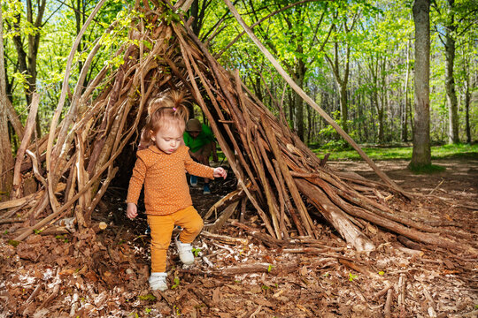 Beautiful girl play in forest hut of branches or wickiup