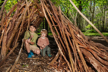 Two boys play build hut of branches in the forest © Sergey Novikov
