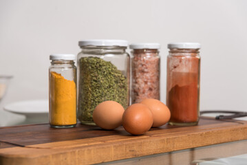 woman's hand holding colorful spices, three eggs, on wood, healthy food, selective focus