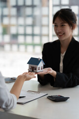 Real estate agents agree to buy a home and give house model to clients at their agency's offices. Concept agreement