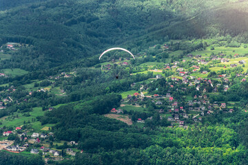 Paraglider on the background of mountains. Houses in the background. Międzybrodzie Bialskie, Poland.