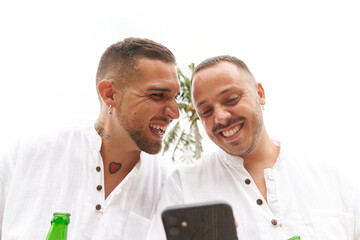 Gay couple laughing together while using the mobile phone outdoors