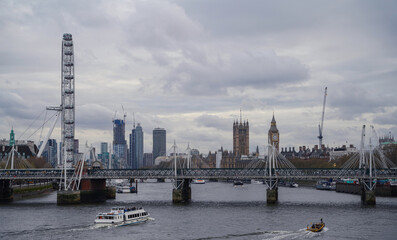 The View on the London Skyline especially the London Eye, the House of Parliament and the Thames with Boats in the foreground. The Photo was taken from the Waterloo-Bridge.