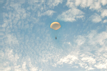 A parachutist flies against the background of a cloudy sky.