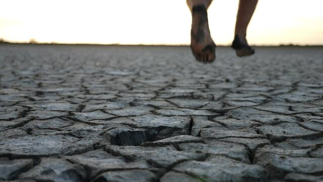 Man running barefoot on bottom of dried lake with mud