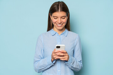 Cute smiling girl reading corporate online chat on phone isolated over blue background