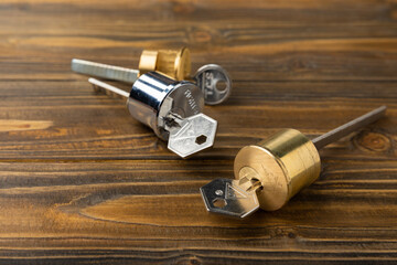 New door lock on a brown wooden background. Patent and keys to the front door. Contact tumbler of the internal mechanism of the cylinder lock and a set of keys. Real estate concept