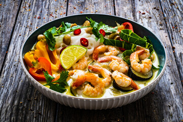 Tom Kha - Thai soup with prawns and rice noodles on wooden table
