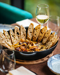 Pan of seafood stew with toasted bread and wine on served table