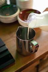 barista pouring milk into a pitcher