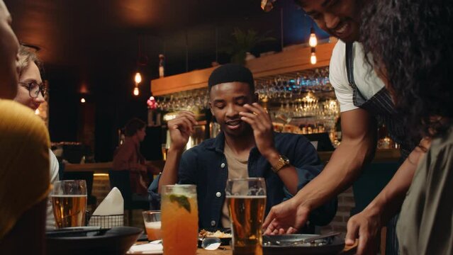 African American Waiter Clearing Plates From Customers Table