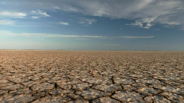 Dynamic shot of cracked soil ground of dried lake or river. 