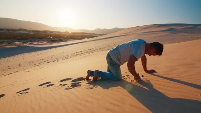 Tired lonely man struggles in the desert with empty bottle of water