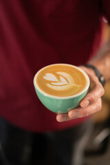 guy in a red t-shirt holding a green cup of coffee