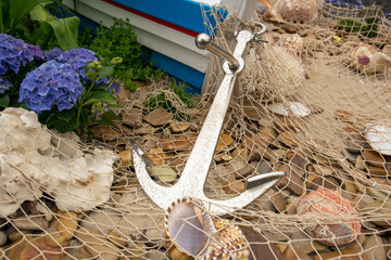 Anchor, fishing net, sea pebbles and shells close-up.