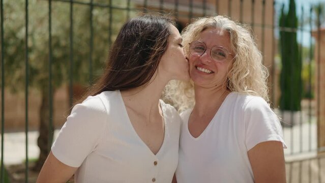 Two women mother and daughter hugging each other and kissing at street