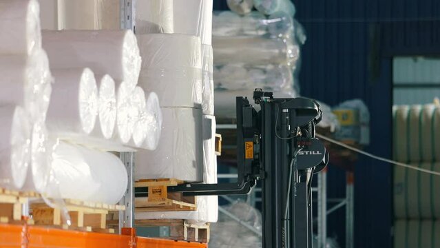 The forklift puts the goods on the shelves of the warehouse. warehouse work. Agrofibre put on the shelf of the warehouse