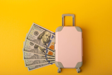 Travel.Vacation money saving concept,beach vacation.Miniature luggage and bundles of hundred dollar bills.Vacations.Copy space.Savings concept for vacation.