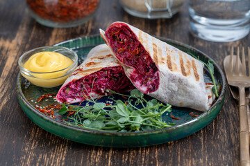 Vegan burrito. Sliced up raw food wrap with red beetroot, feta cheese, prunes, dill and cream sauce