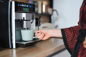 Close-up image of woman hand using coffee machine when making big mug of coffee at home