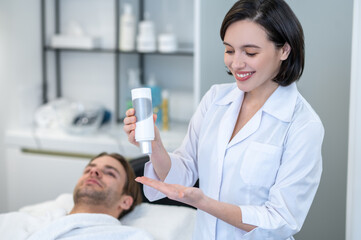 Female cosmetologist holding a bottle with cream