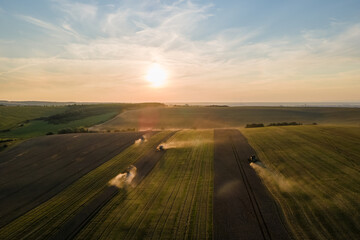Aerial view of combine harvesters working during harvesting season on large ripe wheat field. Agriculture concept
