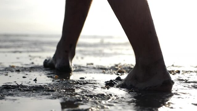 Cinematic shot of man with dirty feet walking barefoot making traces near pond. 