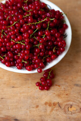 Currants in a bowl on a weeden background. Red berry. Vitamin berries. Copy space.