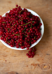 Currants in a bowl on a weeden background. Red berry. Vitamin berries. Copy space.