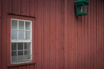 Obraz premium Exterior facade of a wooden barn with a framed glass window and an old lantern hooked on the building