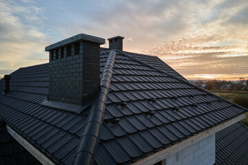 Snow guard for safety in winter on house roof top covered with ceramic shingles. Tiled covering of...