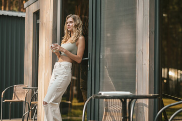 Pensive peaceful female with a coffee cup standing outdoors