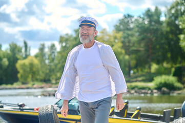 A bearded man in a captains cap looking contented