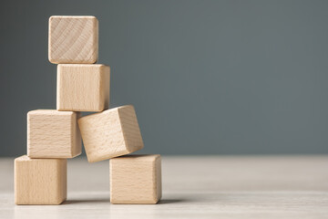 Wooden cubes are built as a tower and risk falling down caused by the only one on the base is in...