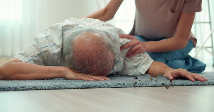 Elderly Asian man fell on the floor and fainted in the living room.Elderly caregivers came to help urgently.Daughter was shocked to see her father fall to the ground.Elderly health problems concept.