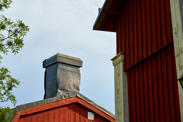 Chimney on an old wooden house with an overcast sky in the background.