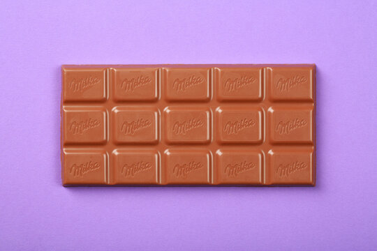 Milka chocolate bar on violet background, flat lay, top view