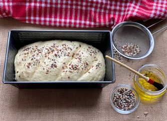 Raw dough in a metal baking dish. Lubricate baked goods with a pastry brush. Bread with sesame.