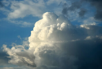 Picturesque sky with thunderstorms cumulus clouds. Blue sky with big clouds, backlit by sun. Air clouds background. Copy space. Selective focus.