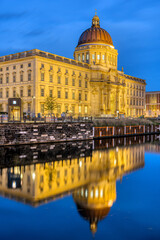 Fototapeta na wymiar The beautiful reconstructed City Palace in Berlin at night reflected in a small canal