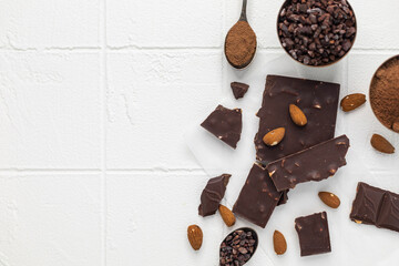 Pieces of chocolate, hot chocolate, chocolate chips and nuts on a white background