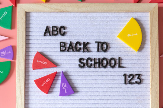 Felt letter board with title Back to school and parts of fractions on a pink background. Education, back to school concept