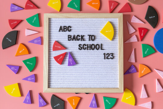 Felt letter board with title Back to school and parts of fractions on a pink background. Education, back to school concept