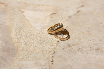 Two gold wedding rings on stone natural background with contrasting shadows