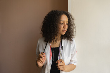 Young doctor with stethoscope in modern office, looking thoughtful.