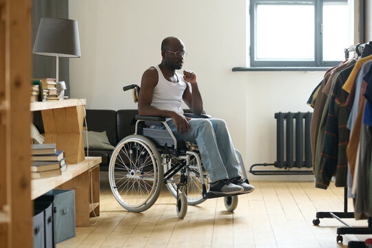 African Young Man Sitting In Wheelchair In The Room And Learning To Live Alone With Disability