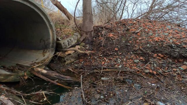 Concrete sewer pipe emptying onto rocky beach.