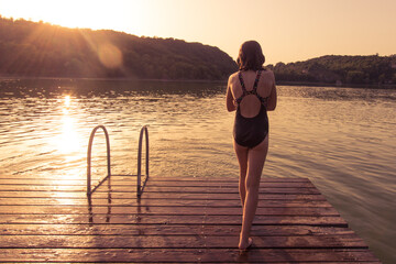 jeune fille au bord d'un lac le soir au coucher de soleil