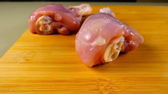 Fresh chicken legs are laid out on a cutting board.