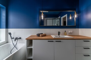 Modern bathroom with blue walls, white furniture and a bathtub